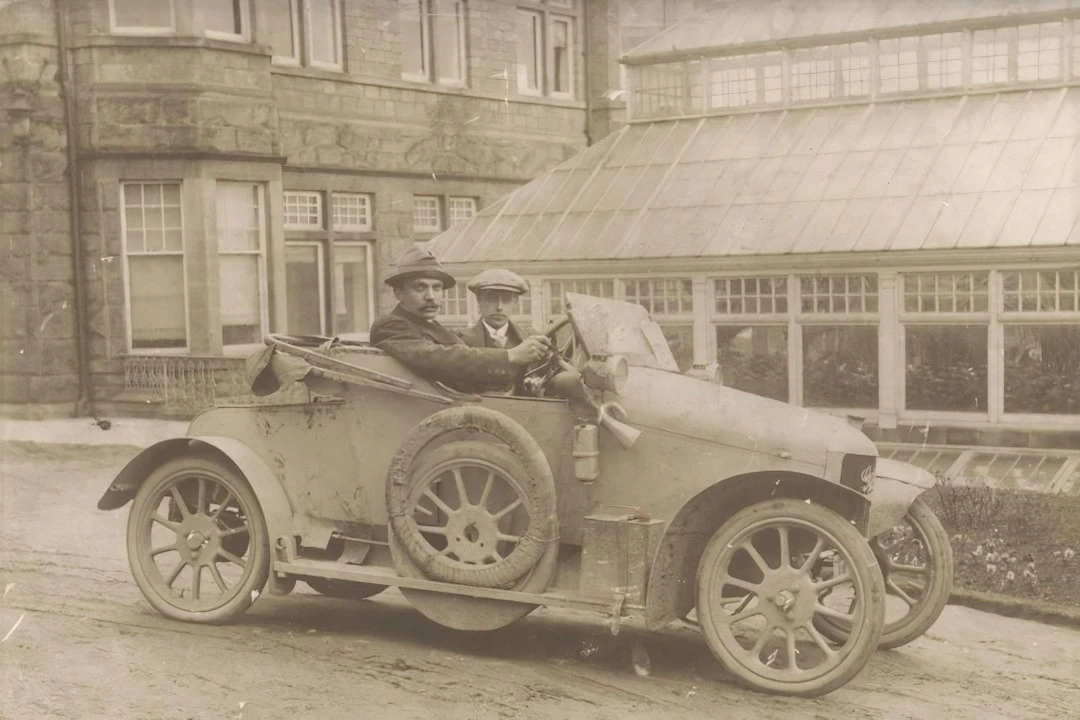 Two men driving and old car.