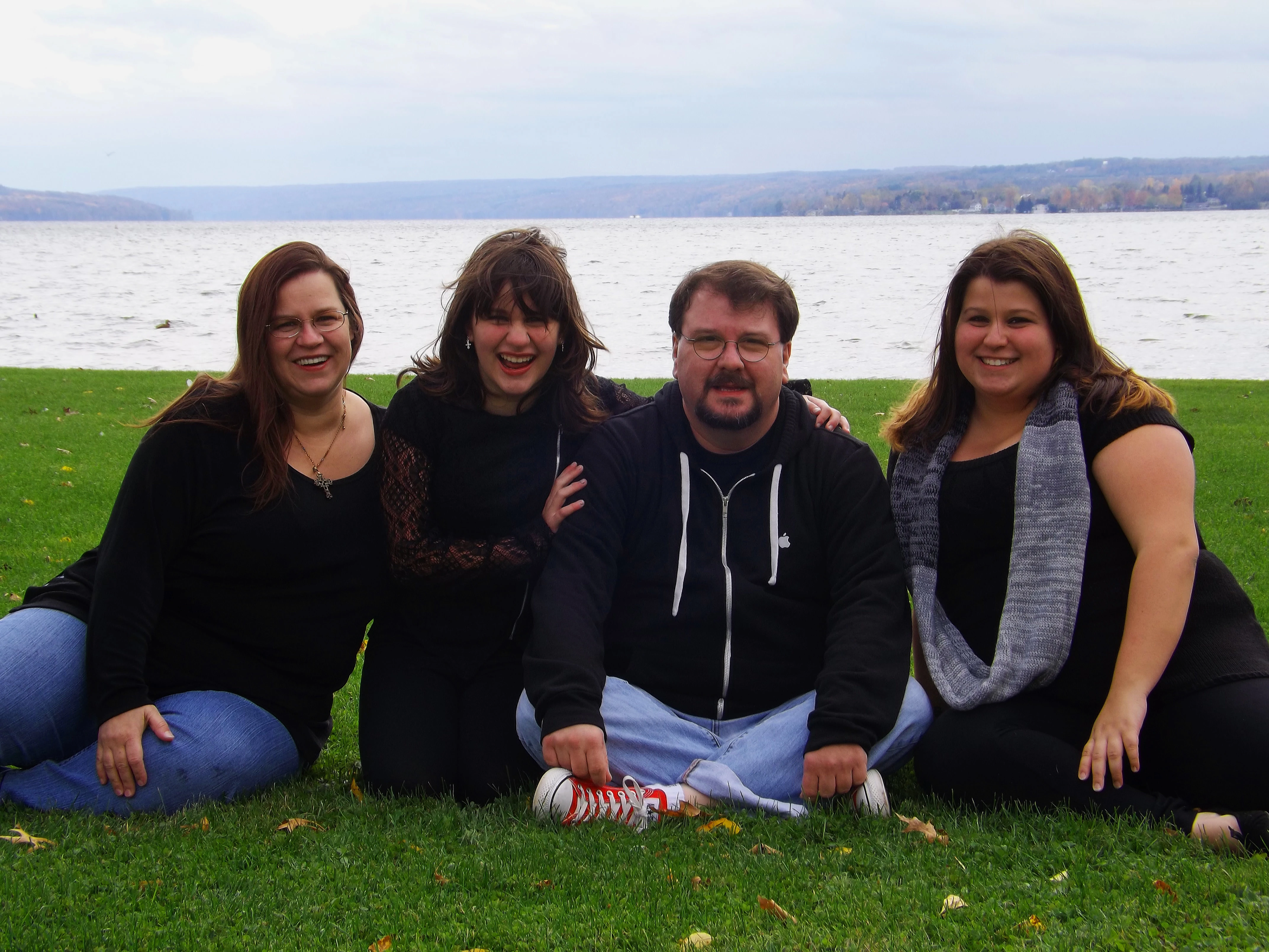 A family picture by a overcast lake.